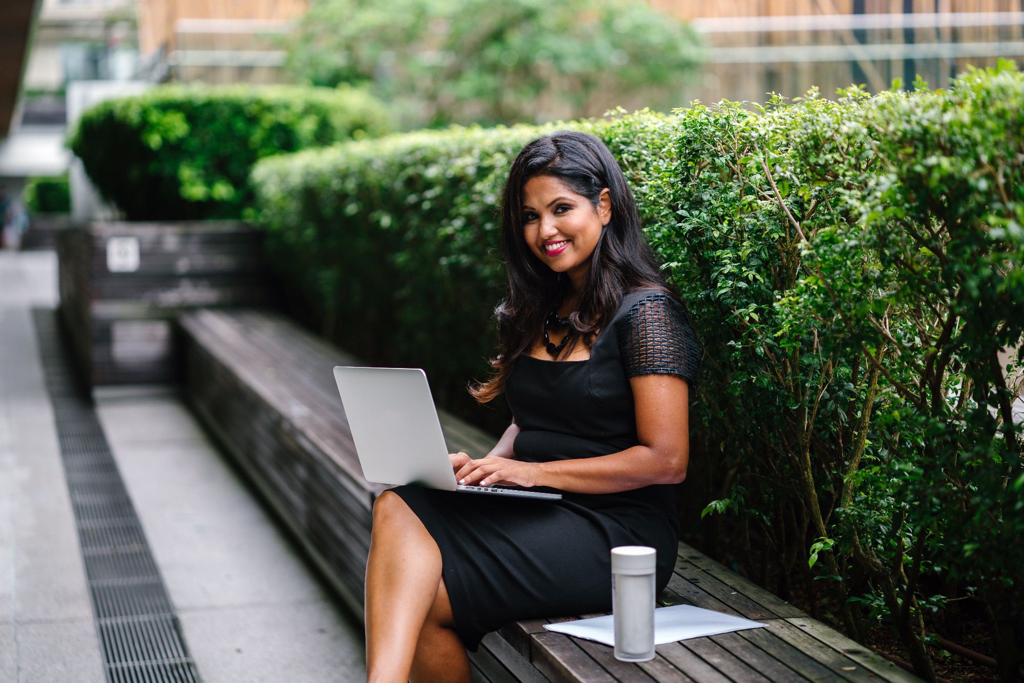 professional woman working on a laptop outside with coffee