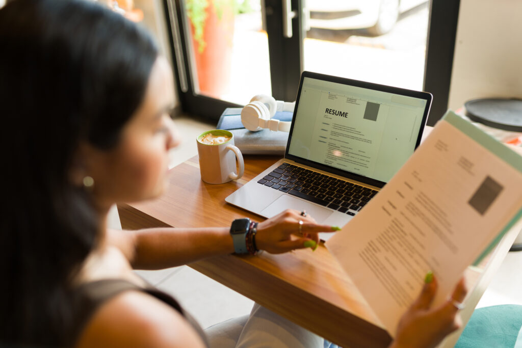 Young woman looking for a new job and sending her online CV resume using the internet zone of the coffee shop